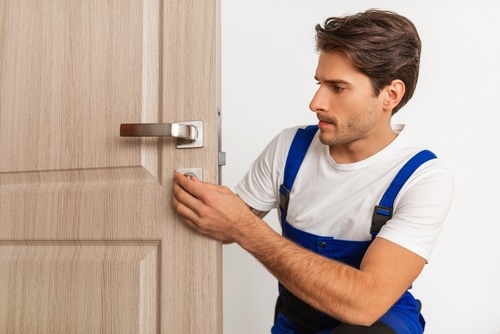 Artisan serrurier vérifiant l'ouverture d'une porte et le fonctionement de la serrure