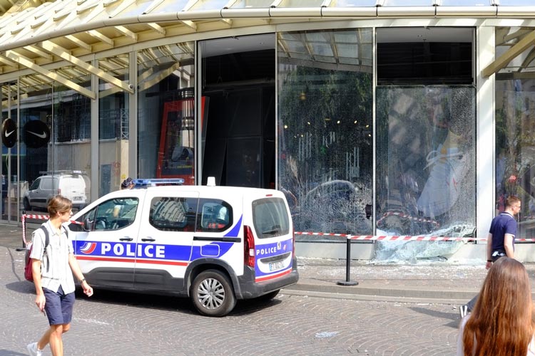 Voiture de police devant une vitirne de magasin brisée